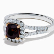 The 18K White Gold GIA Certified Alexandrite and Diamond Ring showcases a cushion-cut Alexandrite surrounded by white diamonds. Its split band is adorned with diamonds, adding elegance, and the ring is displayed against a plain white background.