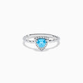 The 925 Sterling Silver Blue Topaz and Diamond Ring features a twisted band, a heart-shaped blue topaz center, and sparkling diamonds, shown against a plain white background.