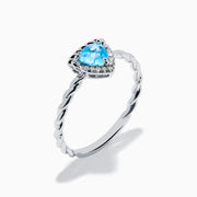The 925 Sterling Silver Blue Topaz and Diamond Ring features a twisted band, a heart-shaped blue topaz center, and sparkling diamonds, shown against a plain white background.