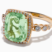 The 14K Rose Gold Green Amethyst and Diamond Halo Cocktail Ring showcases a rectangular light green amethyst center, framed by a sparkling diamond halo with round diamonds accenting the band.