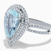The Aquarius 14K White Gold Aquamarine and Diamond Cocktail Ring showcases a pear-shaped aquamarine with a double halo of round diamonds on a white gold band, beautifully displayed against a white background.