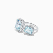 The 14K White Gold Double Aquamarine Ring features two light blue stones—one encircled by diamonds in a halo setting and the other set in a minimal geometric design.
