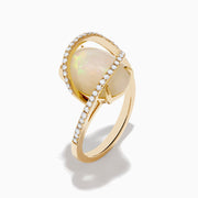 The Aurora 14K Yellow Gold Opal and Diamond Ring showcases a large oval opal center, framed by curved diamond bands, set against a white background.