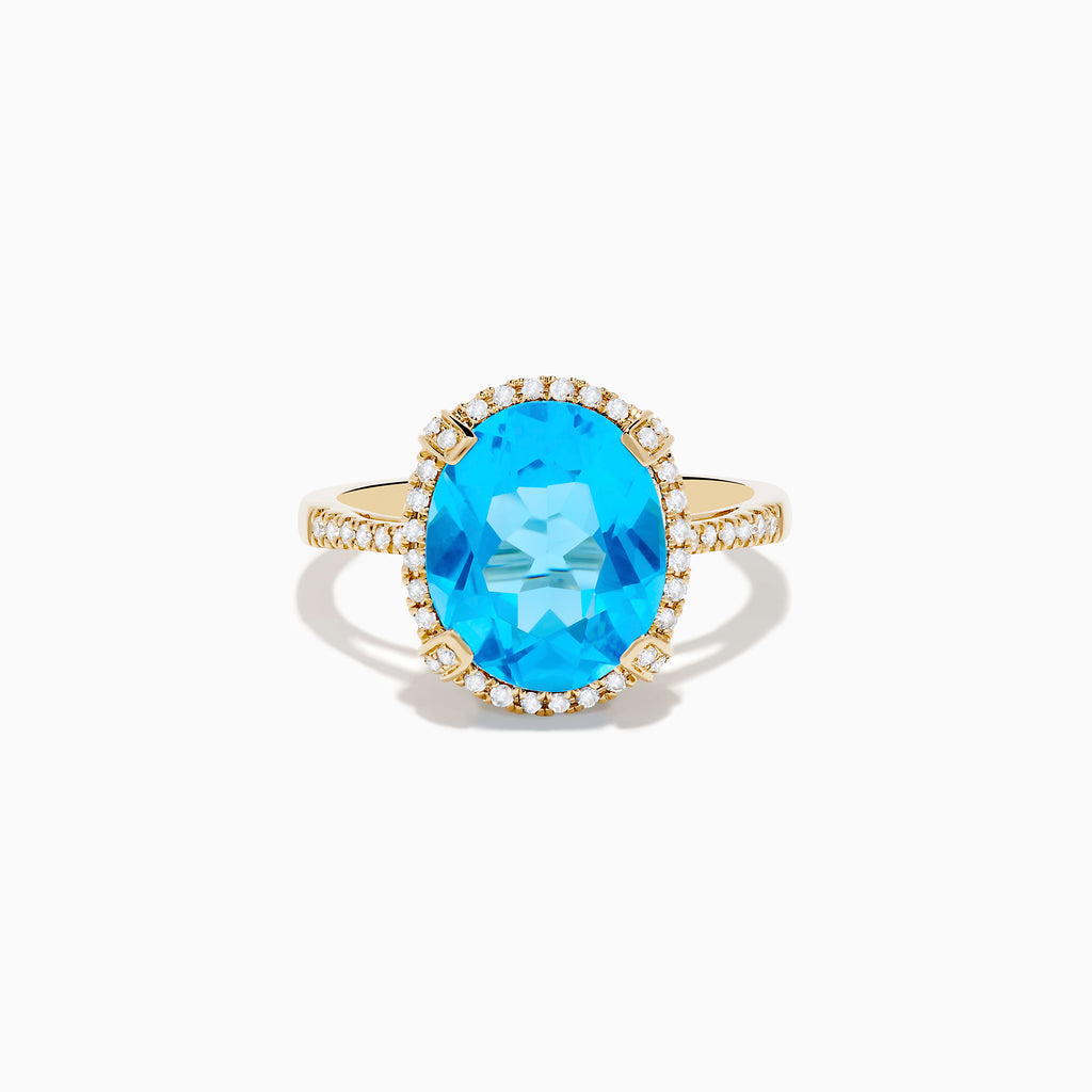 The Ocean Bleu 14K Yellow Gold Blue Topaz Ring showcases a large oval center blue topaz, embraced by a diamond halo and additional diamonds adorning the band.