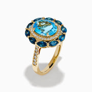The Ocean Bleu 14K Yellow Gold Blue Topaz and Diamond Ring showcases a large oval blue topaz center, haloed by clear diamonds and marquise deep blue stones, all set on a textured yellow gold band.