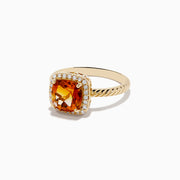 The 14K Yellow Gold Citrine and Diamond Ring showcases a cushion-cut orange citrine at the center, encircled by a halo of diamonds on a textured yellow gold band, elegantly displayed against a white background.