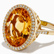 The Sunset 14K Yellow Gold Citrine and Diamond Halo Ring showcases a large oval citrine center stone encircled by a sparkling diamond halo, elegantly displayed on a plain white background.