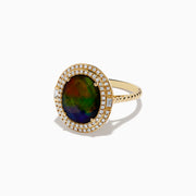 The 14K Yellow Gold Ammolite and Diamond Ring showcases a large oval ammolite center stone, encircled by two halos of sparkling white diamonds, all set in polished yellow gold.