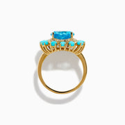 The 14K Yellow Gold Blue Topaz, Turquoise and Diamond Heart Cocktail Ring features a striking heart-shaped blue topaz center, surrounded by a halo of diamonds and an outer border of vibrant round turquoise stones.