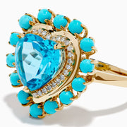 The 14K Yellow Gold Blue Topaz, Turquoise and Diamond Heart Cocktail Ring features a striking heart-shaped blue topaz center, surrounded by a halo of diamonds and an outer border of vibrant round turquoise stones.