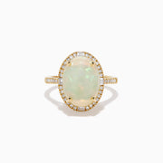 The 14K Yellow Gold Opal and Diamond Halo Cocktail Ring showcases an oval opal centerpiece encircled by a shimmering diamond halo, set against a white background.