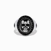 The Mens 925 Sterling Silver Black Spinel Skull Ring showcases a detailed central skull, an oval border set with black spinel stones, twisted metal accents, and small decorative side elements.