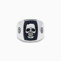 The Men's Sterling Silver Black Spinel Skull Ring features a central raised skull, small black spinel stones surrounding it, and circular engraved symbols on each side of the band.