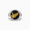 The Mens 925 Sterling Silver and Yellow Gold Eagle Ring features a round black stone face with small black gems, a raised yellow gold eagle at the center, and engraved circular symbols on each side of the band.