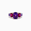 The 14K Rose Gold Amethyst, Rhodolite, and Tanzanite Ring features a central oval amethyst accented by smaller red rhodolite and blue tanzanite gems on each side, displayed on a white background.