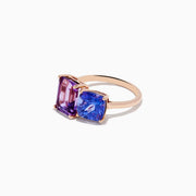 The 14k Rose Gold Amethyst and Tanzanite Toi Et Moi Ring features a rectangular purple amethyst and a cushion-cut blue tanzanite side by side on a minimalist band, displayed against a white background.