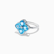 The Ocean Bleu 14K White Gold Ring features four cushion-cut blue topaz gemstones in a floral design, accented by a round diamond at the center.