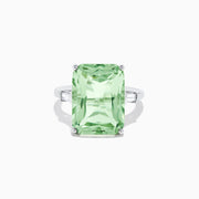 A 14K White Gold Green Amethyst and Diamond 3-Stone Ring features a rectangular, faceted green amethyst center with two small side diamonds, set in white gold and displayed against a white background.