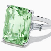 A 14K White Gold Green Amethyst and Diamond 3-Stone Ring features a rectangular, faceted green amethyst center with two small side diamonds, set in white gold and displayed against a white background.