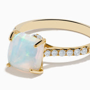 The Aurora 14K Yellow Gold Opal and Diamond Ring features a rectangular opal center accented by small round diamonds along the band, shown against a white background.