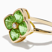 The 14K Yellow Gold Peridot and Diamond Ring displays a clover-shaped design with four faceted green peridots and a central round diamond, shown against a white background.