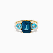The 14K Yellow Gold Sky Blue and London Blue Topaz 3 Stone Ring features a large rectangular blue topaz flanked by two heart-shaped stones, all set in yellow gold. A stunning piece for any occasion.