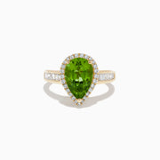 The 14K Yellow Gold Pear Shaped Peridot and Diamond Cocktail Ring features a pear-cut peridot center, a halo of white diamonds, and baguette-cut diamonds along the band for a dazzling, elegant look.