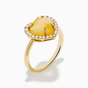 The Aurora 14K Yellow Gold Opal and Diamond Heart Halo Ring features a heart-shaped opal at the center, surrounded by a diamond halo.