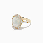 The 14K Yellow Gold Opal and Diamond Ring showcases an oval opal encircled by a halo of round diamonds, with more diamonds along the band, displayed on a white background.