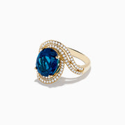 The Ocean Blue 14K Gold London Blue Topaz and Diamond Ring showcases a large oval topaz centerpiece, accented by two wavy rows of sparkling diamonds.