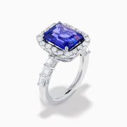 The Effy Hematian 18K White Gold Tanzanite and Diamond Halo Ring showcases a large rectangular blue tanzanite at the center, encircled by a diamond halo with additional diamonds set along the band.