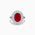 The 18K White Gold Ruby and Diamond Double Halo Ring features an oval ruby encircled by double diamond halos on a sleek white gold band, showcased against a white background.