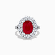 The 18K White Gold Ruby and Diamond Double Halo Ring features an oval ruby encircled by double diamond halos on a sleek white gold band, showcased against a white background.