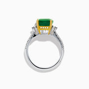 The 18K Two Tone Gold Emerald and Diamond Ring features a large square-cut green emerald in an 18K gold prong setting, with a white metal band accented by small round diamonds on each side.