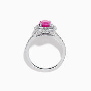 The 18K White Gold Pink Sapphire and Diamond Halo Ring showcases an oval pink sapphire center, encircled by a halo of baguette and round-cut diamonds, with more diamonds adorning the band.