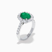 The Effy Hematian 18K White Gold Oval Emerald and Diamond Halo Ring features a vibrant oval emerald at the center, surrounded by a sparkling diamond halo with additional diamonds set along the elegant band.