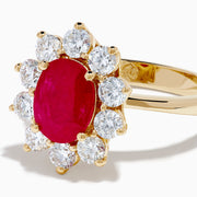 The 14K Yellow Gold Natural Ruby and Diamond Lady Di Ring showcases an oval natural ruby center with a halo of round white diamonds, set against a white background.