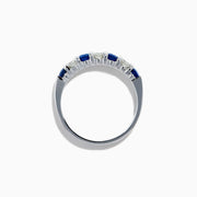 The 14K White Gold 7-Stone Blue Sapphire & Diamond Band, 0.65 TCW, features alternating round blue sapphires and sparkling white diamonds in a row on the band, shown against a white background.