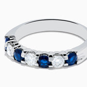 The 14K White Gold 7-Stone Blue Sapphire & Diamond Band, 1.00 TCW, features alternating round blue sapphires and white diamonds, displayed on a plain white background.
