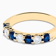 The 14K Yellow Gold 7-Stone Blue Sapphire & Diamond Band (1.00 TCW) features alternating blue sapphires and clear diamonds in a row along the gold band, shown on a white background.