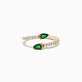 The 14K Yellow Gold Emerald and Diamond Bypass Ring showcases two pear-shaped emeralds on an open gold band accented by round white diamonds, elegantly displayed on a white background.