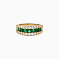 The Brasilica 14K Yellow Gold Emerald and Diamond Wide Band Ring features a symmetrical design with two rows of round diamonds framing horizontally set rectangular green emeralds, offering timeless sophistication.