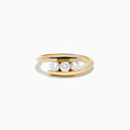 The D'Oro 14K Yellow Gold Diamond Bypass Ring features three round white diamonds in a row and a modern, open, curved band design, shown on a white background.