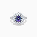 The 18K White Gold GIA Certified Zoisite and Diamond Ring features a cushion-cut blue-purple zoisite center stone with a starburst diamond halo, creating a striking look against the white gold setting.