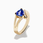 The Nahla 14K Yellow Gold Tanzanite and Diamond Ring features a triangular blue tanzanite center, accented by a curved row of sparkling round white diamonds on one side of the band.