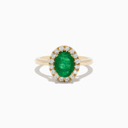 The 14K Yellow Gold Emerald and Diamond Ring features an oval green emerald center stone encircled by a halo of small round white diamonds, shown against a white background.