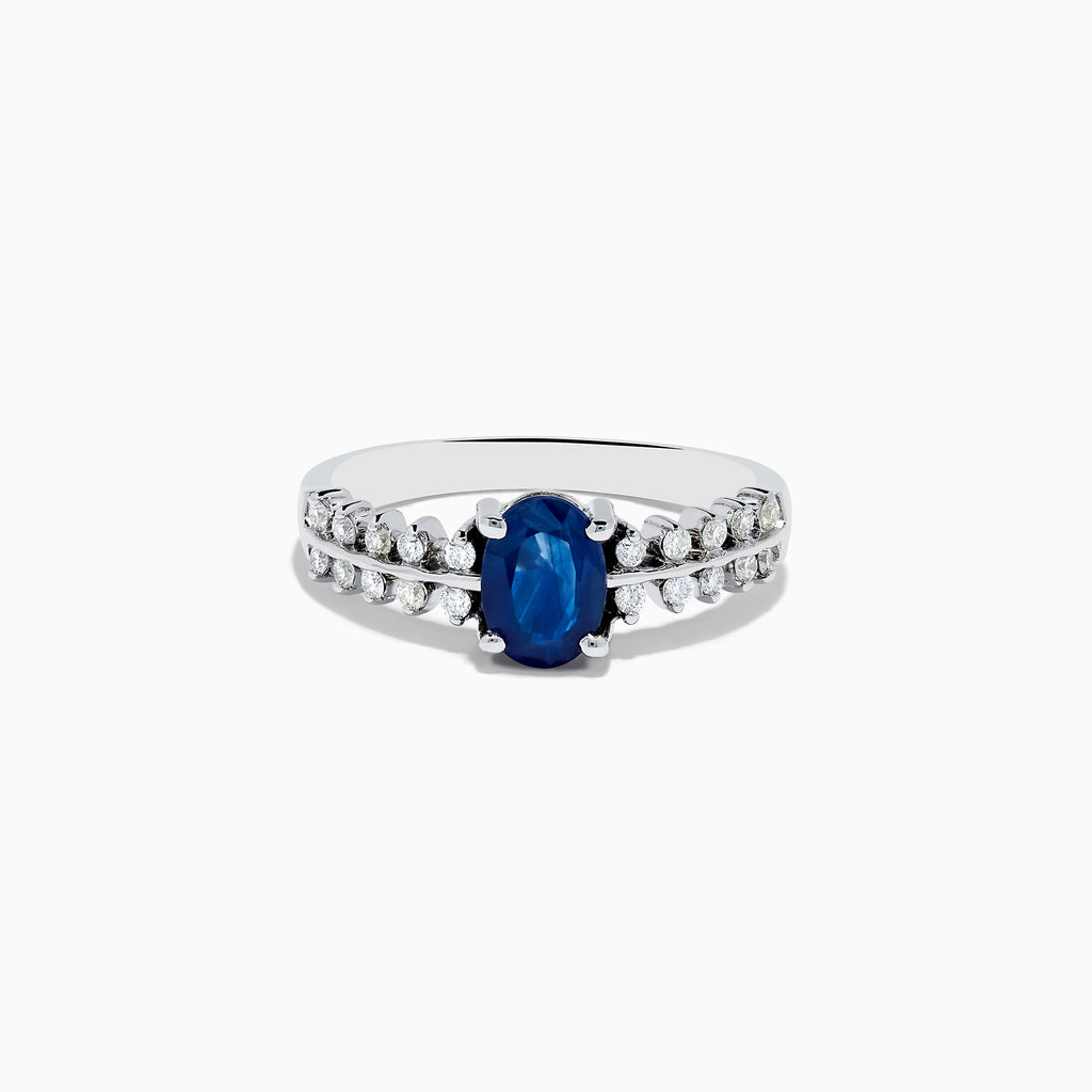 The 14K White Gold Blue Sapphire and Diamond Ring showcases an oval blue sapphire center, accented by two rows of round diamonds on each side, elegantly set against a white background.