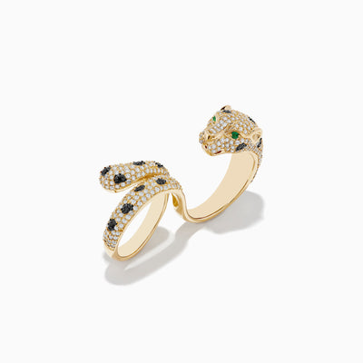 The Signature 14K Gold Emerald, Black and White Double Finger Ring features a panther design wrapping around two fingers, with emerald-green eyes, black spots, and small white gemstones encrusted on its body and tail.