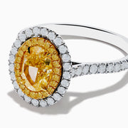 The 18K Two Tone Gold White and GIA Certified Yellow Diamond Double Halo Ring features a central oval yellow diamond, surrounded by white diamonds and additional diamonds set along the band.