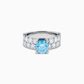 The Lab Grown Blue Diamond Round Brilliant Solitaire Ring in 14K White Gold features a striking round blue diamond center, accented by two rows of sparkling clear diamonds along the band, shown on a white background.